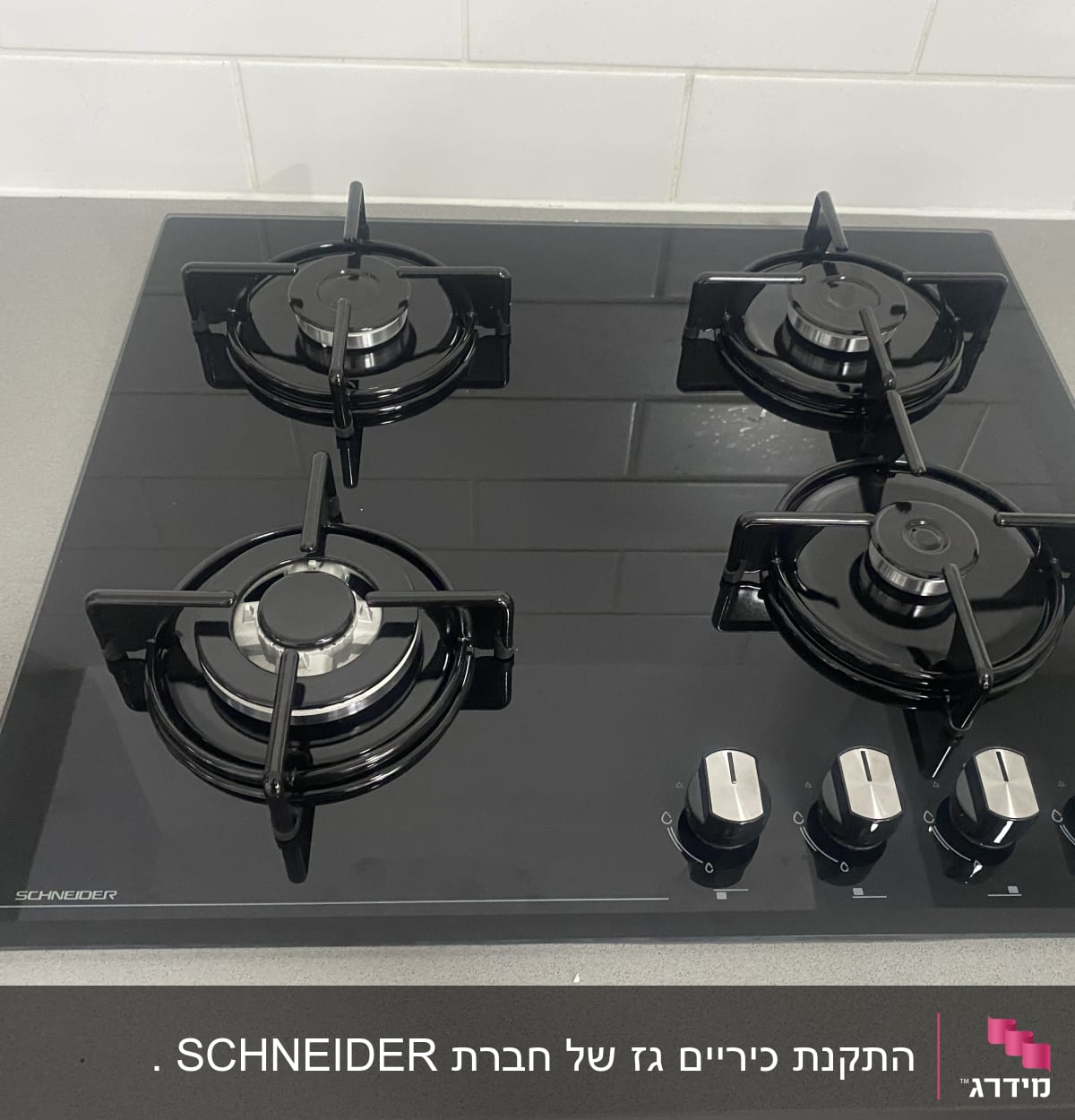כיריים גז שחורות עם ארבעה מבערים וכפתורי שליטה כסופים